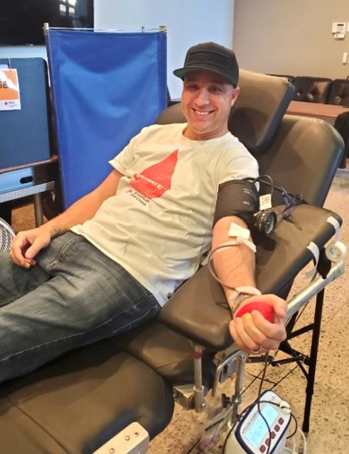 A man sitting in a chair getting his blood pressure checked at a blood drive.