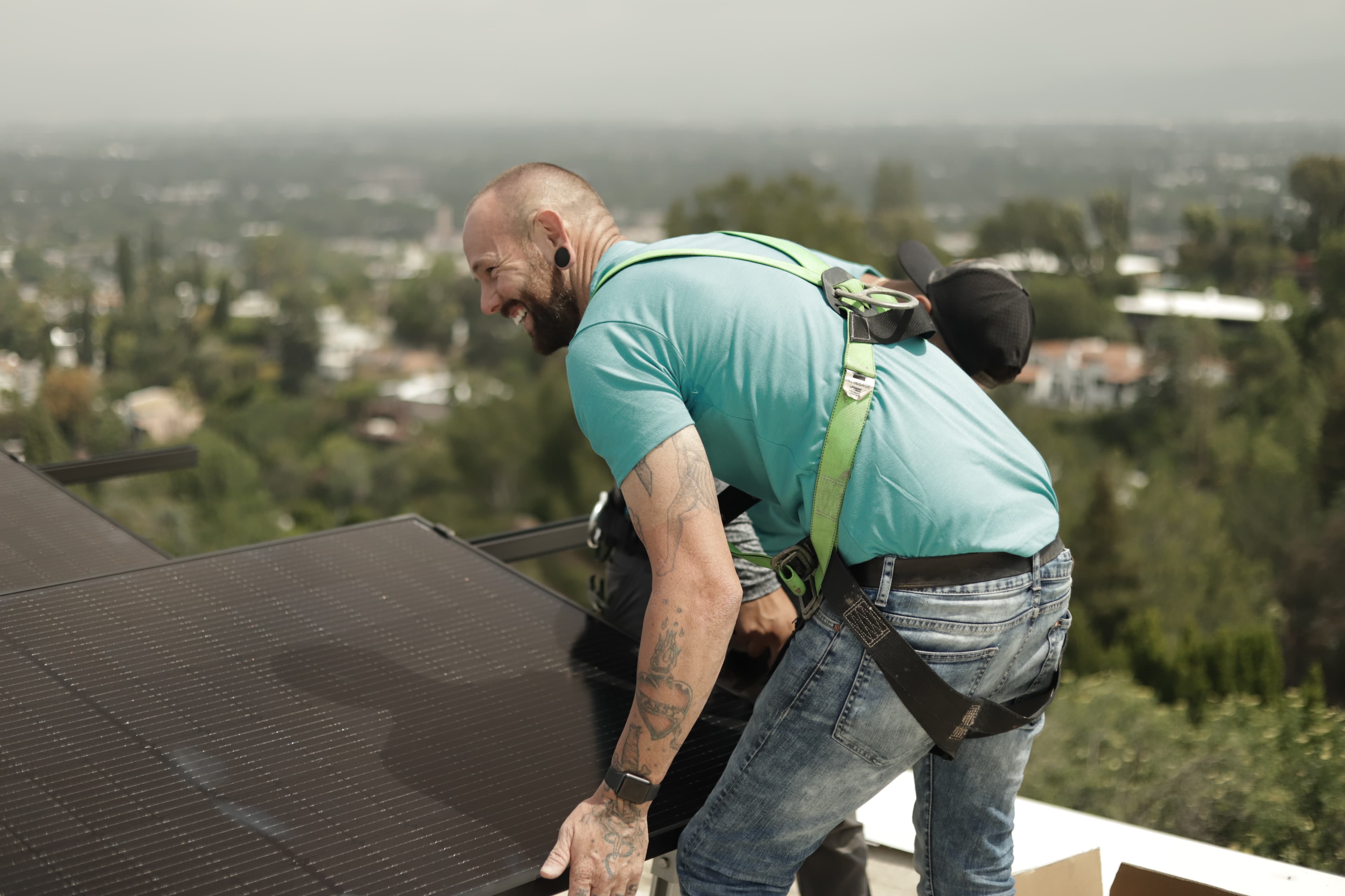 A man in a light blue shirt and jeans installing a solar panel